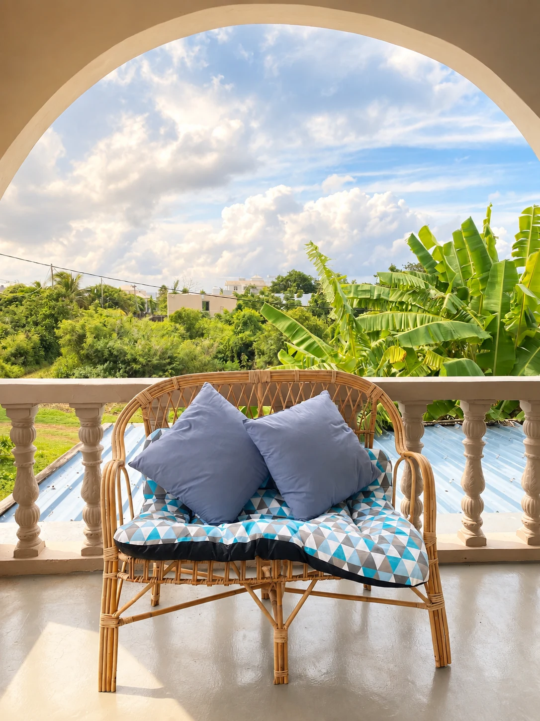 Fauteuil en rotin sur la terrasse avec vue dégagée et végétation tropicale
